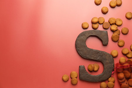 Saint Nicholas (Sinterklaas) day. Chocolate letter S and kruidnoten cookies on red background, flat lay. Space for textの写真素材