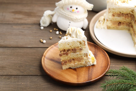 Piece of delicious cake with Christmas decor on wooden table, closeup. Space for text
