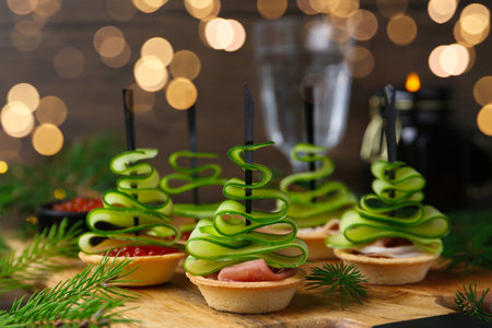 Christmas trees made with cucumber, red caviar, ham and festive decor on table, closeupの写真素材