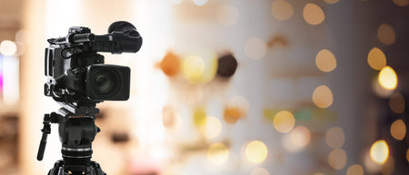 Video camera on stand against blurred background with bokeh lights. Banner design