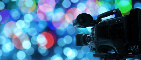 Video camera against blurred lights on color background, bokeh effect. Banner designの写真素材