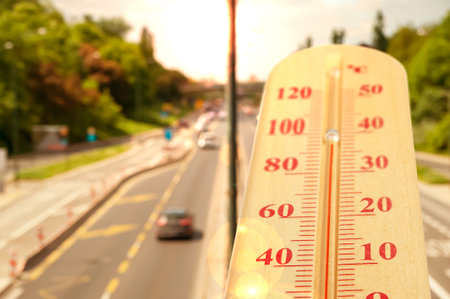 Thermometer showing high temperature against road in city during hot dayの写真素材