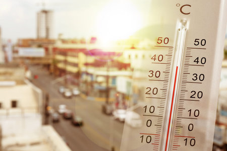 Thermometer showing high temperature, double exposure with city street during hot day