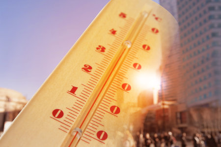 Thermometer showing high temperature with city street during hot day