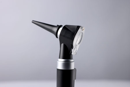 Hearing test. Modern otoscope on light gray background, closeup
