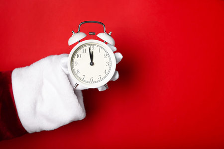 Santa Claus with alarm clock on red background, closeup with space for text. New Year greeting card
