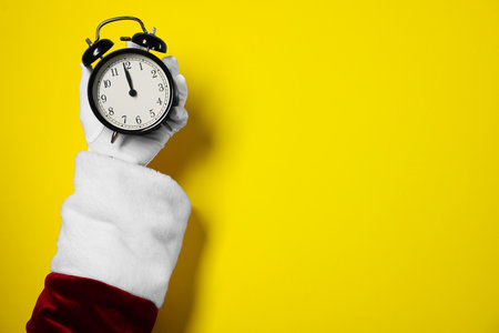 Santa Claus with alarm clock on yellow background, closeup with space for text. New Year greeting cardの写真素材