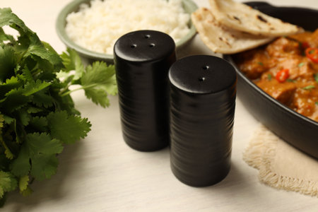 Salt, pepper shakers, parsley, chicken tikka masala and rice on wooden table, closeupの写真素材