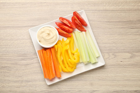 Different fresh vegetables and sauce on wooden table, top view