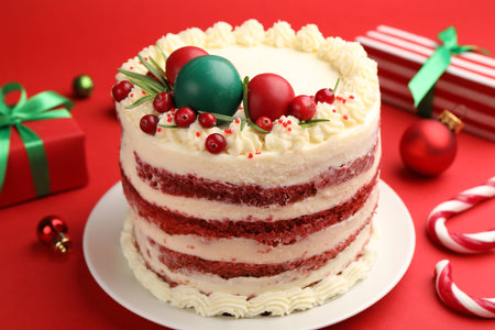 Delicious sponge cake with Christmas decor and berries on red background, closeupの写真素材
