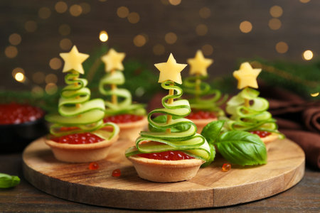 Christmas tree shaped tartlets made with red caviar, cucumber and cheese on wooden table, closeupの写真素材