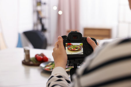 Woman taking picture of meal at table in studio, closeup with space for text. Professional food photographyの写真素材