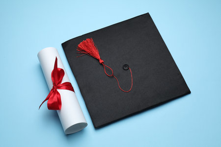 Diploma and graduation hat on light blue background, above viewの写真素材