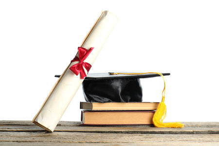Diploma, books and graduation hat on wooden table against white backgroundの写真素材