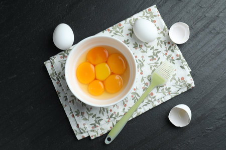 Raw eggs, yolks and brush on black table, flat layの写真素材
