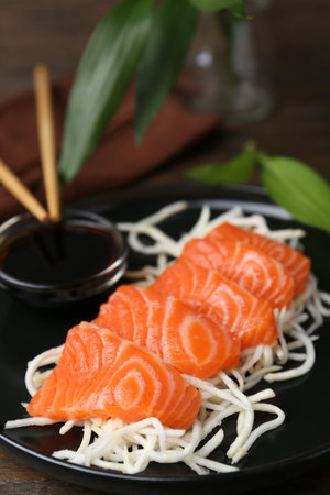 Fresh salmon sashimi with sliced radish and soy sauce on wooden table, closeupの写真素材