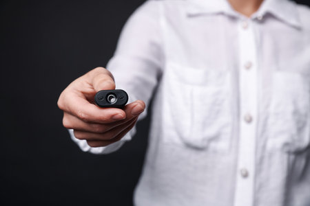 Young woman with hidden spy camera on black background, closeupの写真素材