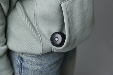 Young woman with hidden spy camera in her pocket on light gray background, closeupの写真素材