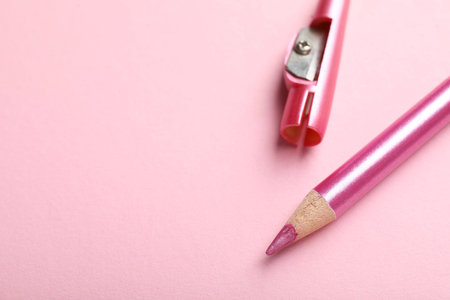 Bright eye pencil and sharpener on pink background, closeup. Space for textの写真素材