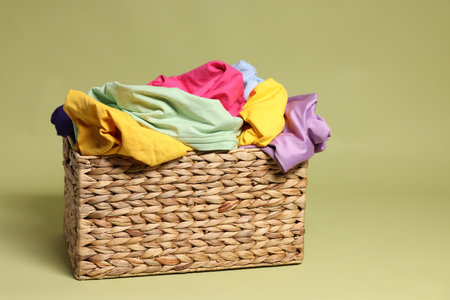Laundry basket with clothes against olive backgroundの写真素材