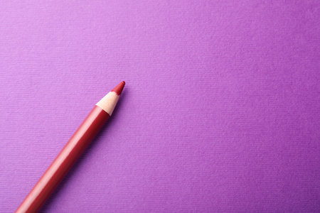 Red pencil on purple background, top view. Space for textの写真素材