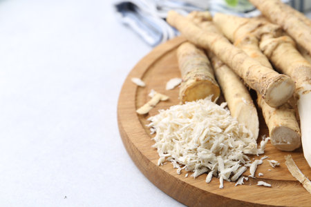 Whole and gratified horseradish roots on light gray table, closeup. Space for textの写真素材