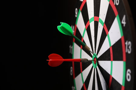 Dartboard with darts on black background, closeup. Space for textの写真素材