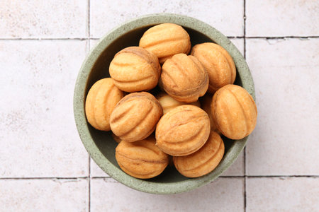 Delicious nut shaped cookies with boiled condensed milk in bowl on light tiled table, top viewの写真素材