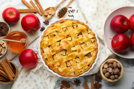 Tasty homemade apple pie and ingredients on white marble table, flat layの写真素材