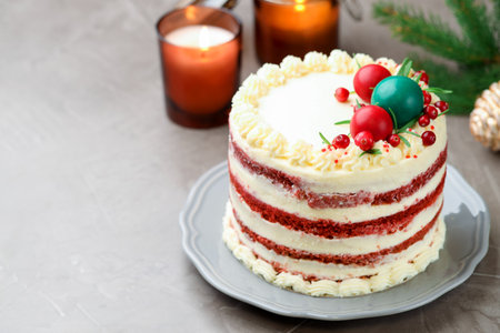 Delicious sponge cake with Christmas decor and red currants on gray textured table, closeup. Space for textの写真素材