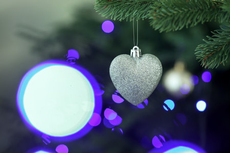 Fir tree with Christmas lights and heart shaped ornament, closeup. Bokeh effectの写真素材