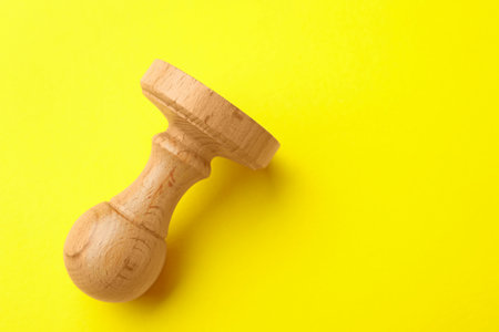 One wooden stamp on yellow background, top view. Space for textの写真素材