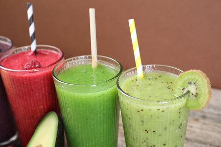 Different tasty smoothies in glasses and ingredients on wooden table, closeupの写真素材