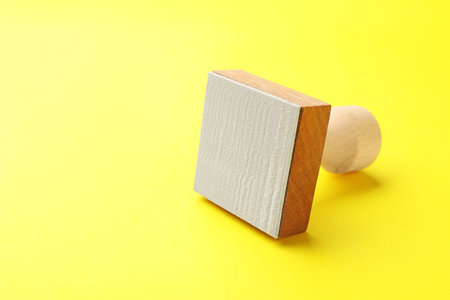 One wooden stamp on yellow background, closeup. Space for textの写真素材