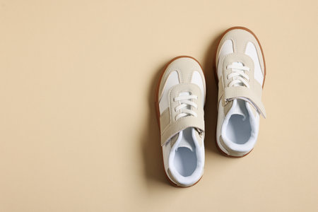 Pair of stylish kid's sneakers on beige background, flat lay. Space for textの写真素材