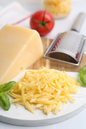 Grater, basil, grater and piece of cheese on white table, closeupの写真素材
