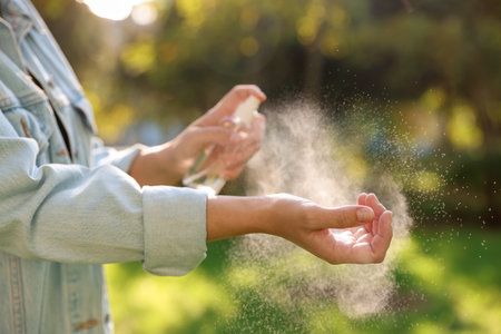 Woman spraying tick repellent onto hand in park, closeupの写真素材