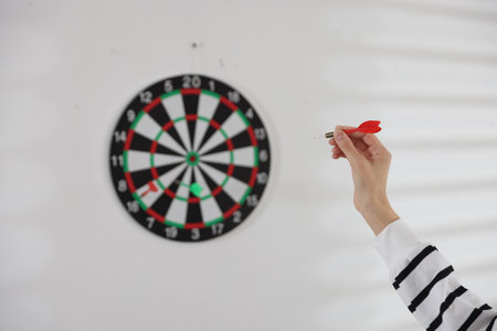 Woman with dart aiming at dartboard indoors, selective focusの写真素材