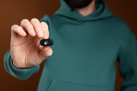Man with hidden camera on brown background, closeup