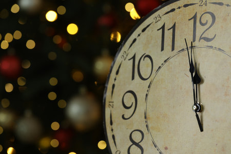 Wall clock against dark background with blurred lights, closeup with space for text. New Year greeting cardの写真素材