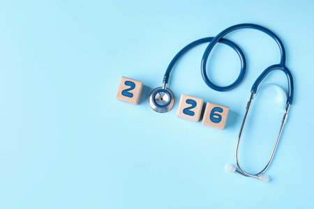 Cubes with numbers and stethoscope on light blue background, top view