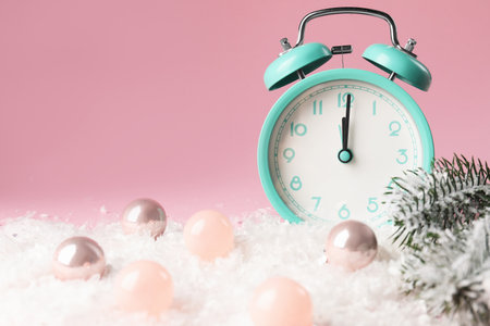 Alarm clock, baubles and fir tree branches on artificial snow against pink background, closeup with space for text. New Year greeting cardの写真素材
