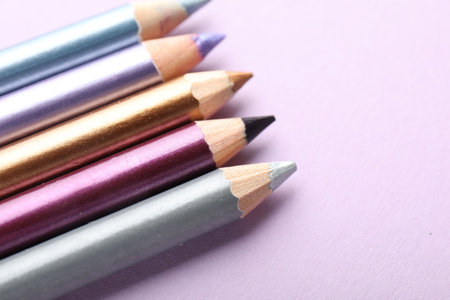 Eye pencils on lilac background, closeup. Space for textの写真素材