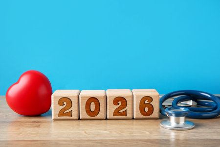Cubes with numbers, heart and stethoscope on table against blue background