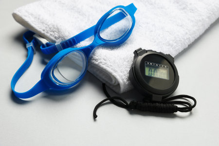 Towel, goggles and digital stopwatch on light gray background, closeupの写真素材