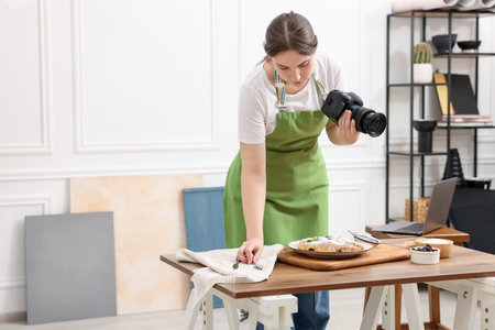 Woman creating composition with croissants at table in studio, space for text. Professional food photographyの写真素材