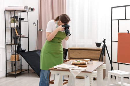 Woman taking picture of croissants at table in studio. Professional food photographyの写真素材