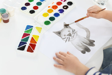 Little boy with brush drawing cat at white table, closeupの写真素材