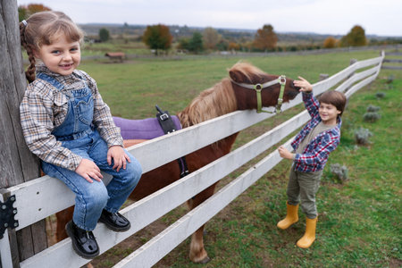 Equine assisted therapy. Cute children with beautiful pony at paddock, selective focus. Lovely domesticated petの写真素材