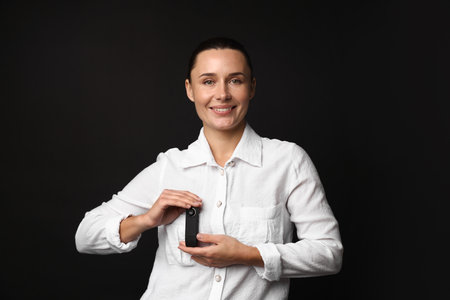 Young woman with camera in her pocket on black background